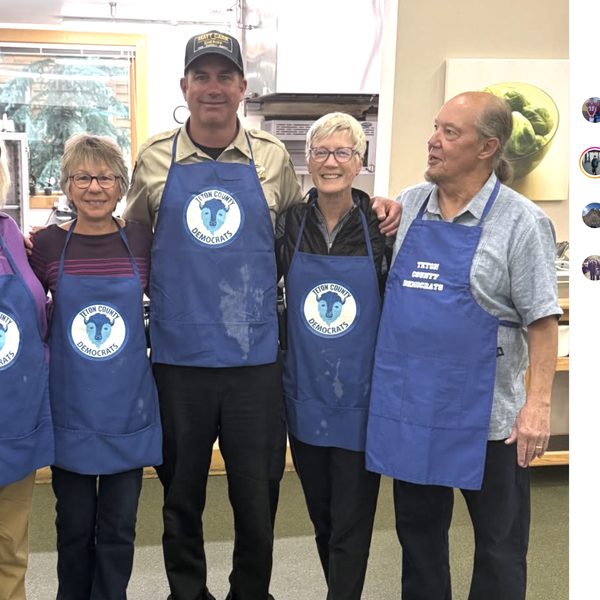 Thumbnail of Exhibit K, Carr in uniform shirt, campaign cap, and Teton County Democrats apron on the County account.